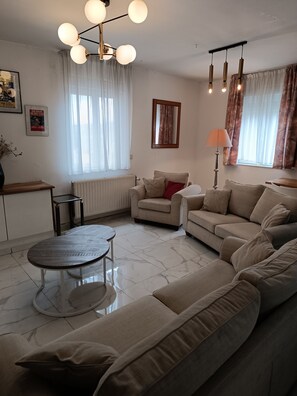 Ein modernes Wohnzimmer mit einer Sofagarnitur, einem Couchtisch und einem Essbereich.