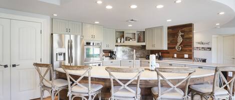 A modern kitchen with a central island, bar stools, and a wooden accent wall.