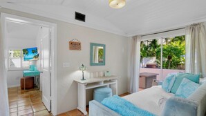 Une chambre à coucher comprenant un lit, un bureau, une chaise, un téléviseur et une fenêtre donnant sur un paysage verdoyant.