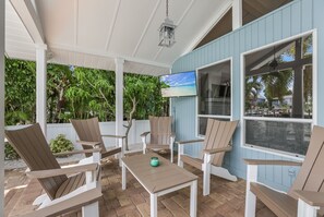 Relax in style with Adirondack chairs and a table, surrounded by lush greenery and a clear view.