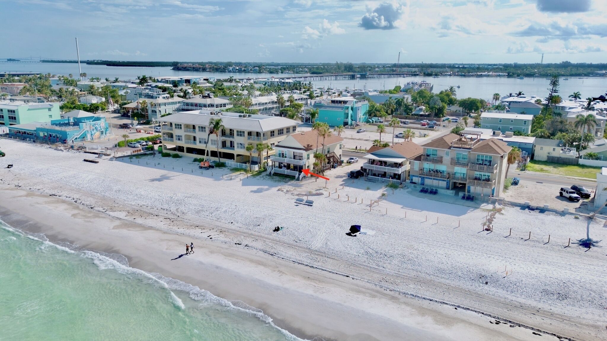 A coastal hotel with multiple buildings, a beach, and a pier in the background.