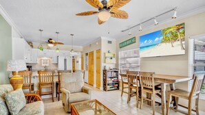 A spacious living area with a dining table, chairs, a sofa, and a ceiling fan. - Beachfront Rental with Ocean Views, Close to Restaurants and Shopping! (Bradenton Beach)