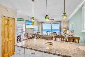A kitchen with a large island, a dining area with a view of the ocean, and a sign that reads 'CH HOUSE'. - Beachfront Rental with Ocean Views, Close to Restaurants and Shopping! (Bradenton Beach)
