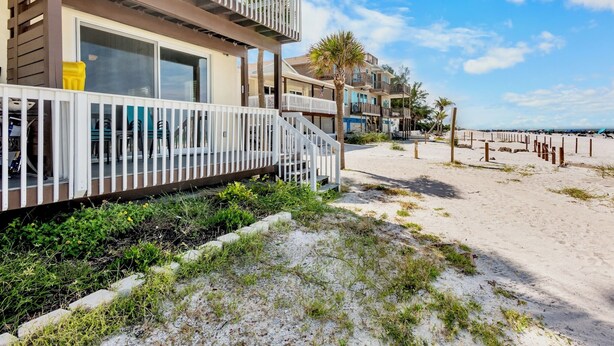 A beachfront property with multiple-story buildings, balconies, and a sandy beach area. - Beachfront Rental with Ocean Views, Close to Restaurants and Shopping! (Bradenton Beach)