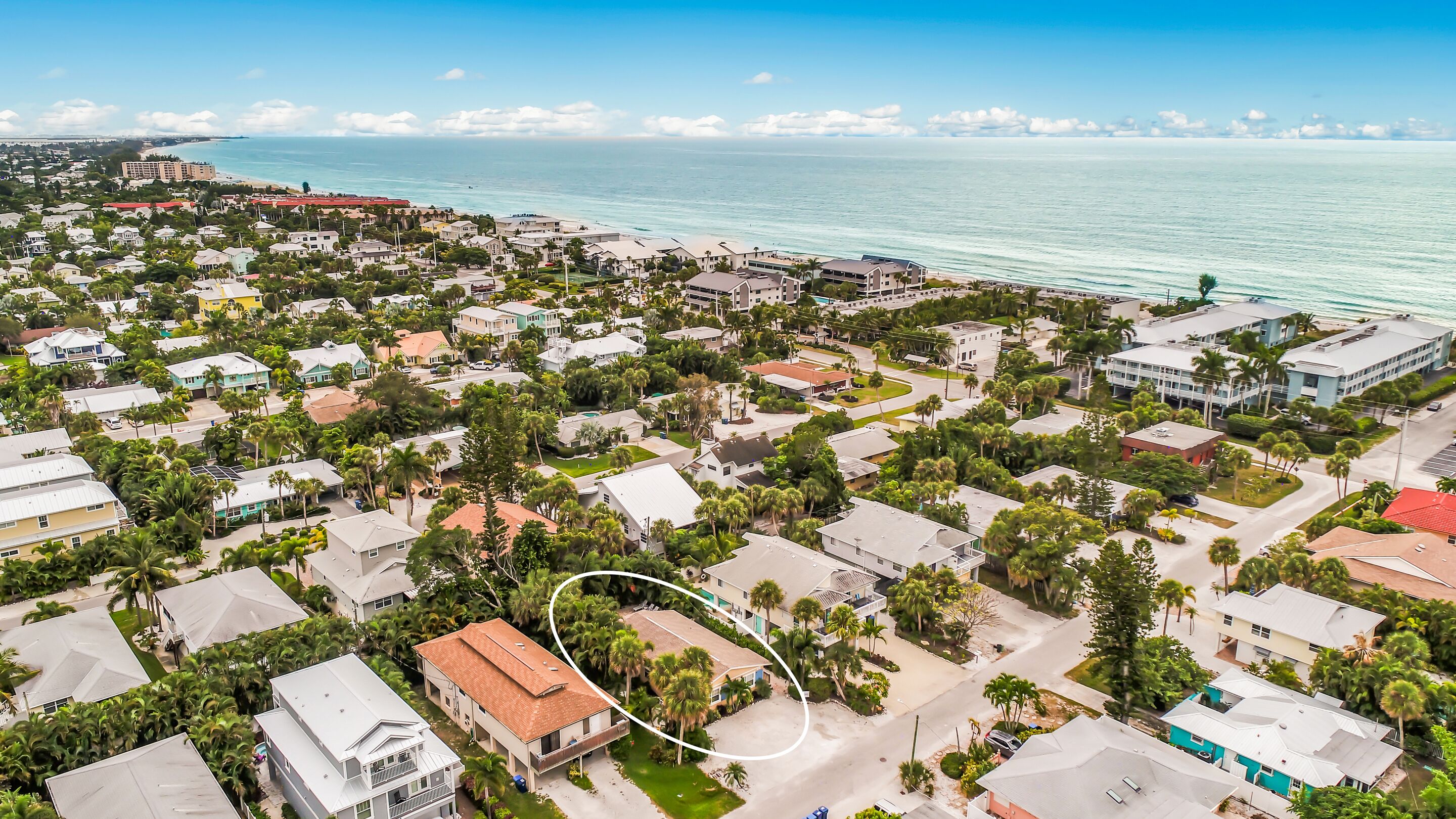 An aerial view of a coastal residential area with houses, roads, and a beach.