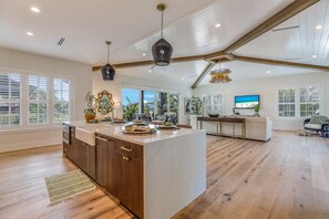 A spacious kitchen with a large island, wooden cabinets, and a modern pendant light.
