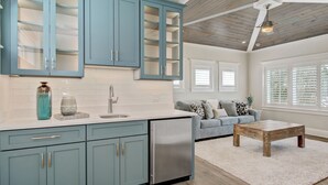 A modern kitchen with teal cabinets, a stainless steel refrigerator, and a white countertop.