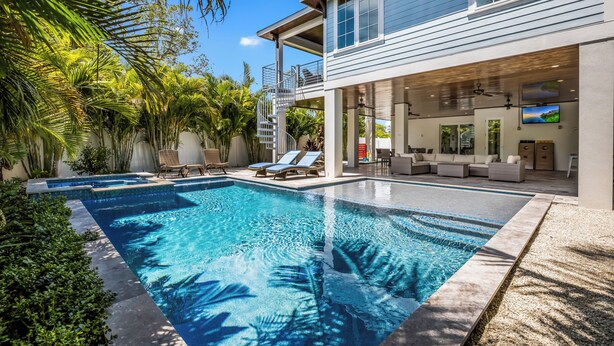 A modern house with a swimming pool, outdoor seating, and a covered patio area.