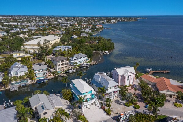 An aerial view of a coastal residential area with houses, docks, and a marina.