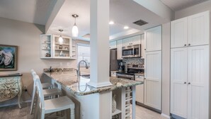 A modern kitchen with white cabinetry, granite countertops, and stainless steel appliances.