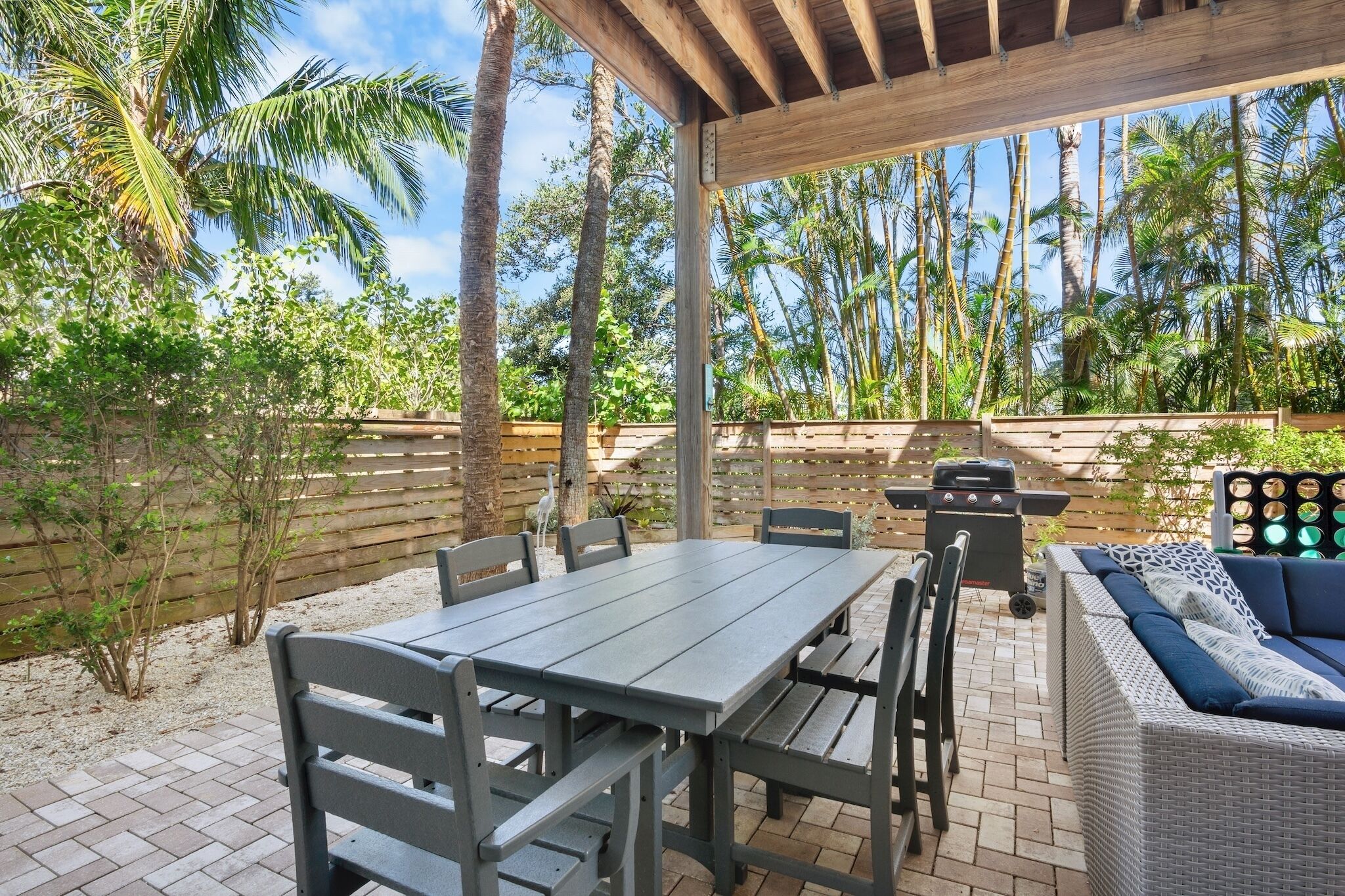An outdoor patio with a table and chairs, a sofa, and a grill.