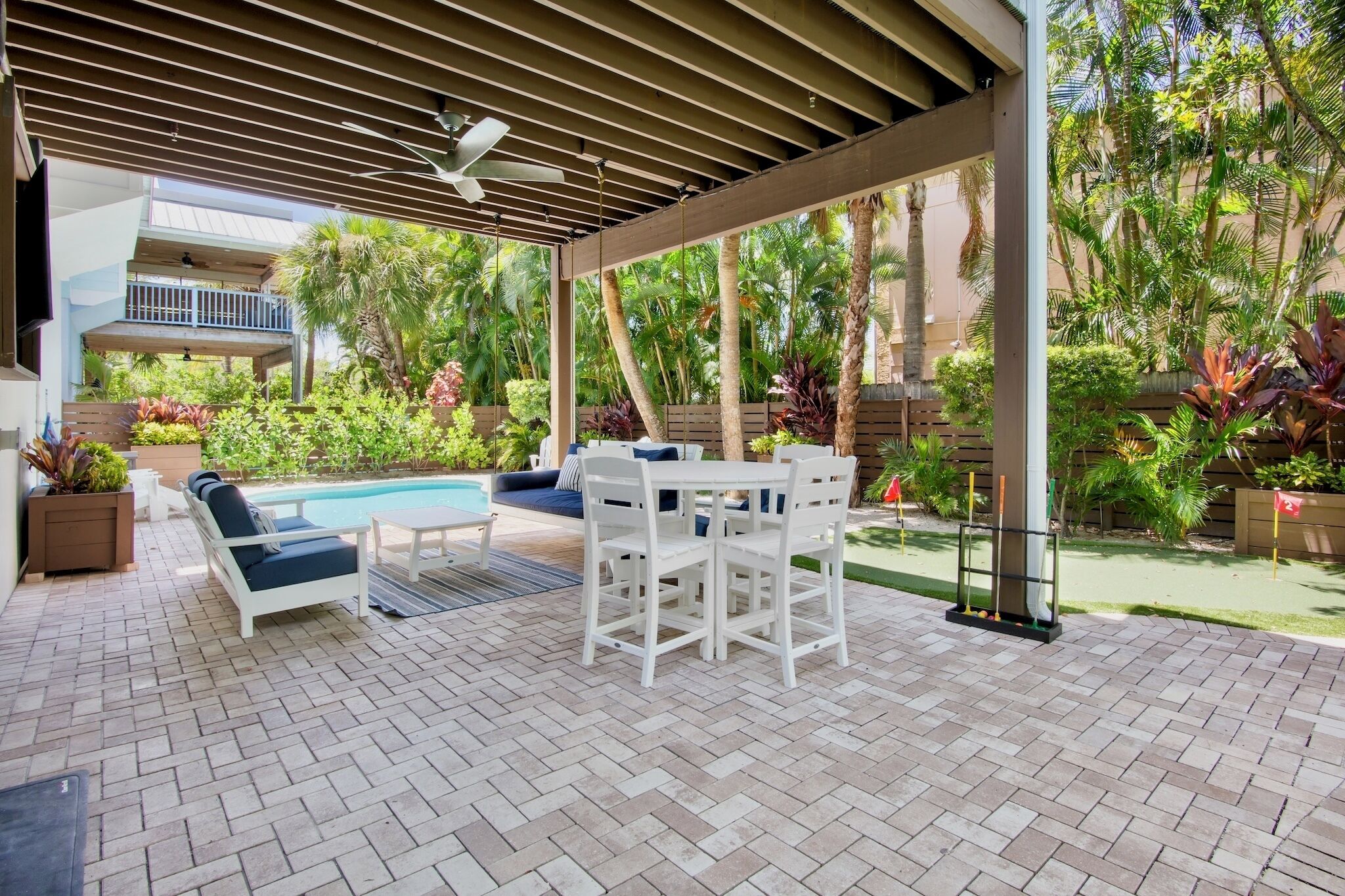 Eine Außenpatio mit Pool, Sitzbereich und üppiger Bepflanzung.