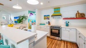 Une cuisine moderne avec des meubles blancs, un îlot central et un four en acier inoxydable.