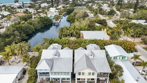 Une zone résidentielle côtière avec des maisons, une rivière et des palmiers.