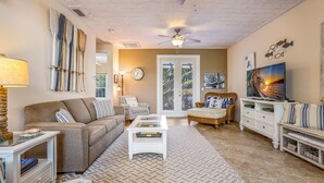 A living room with a sofa, armchairs, a coffee table, a TV, and a ceiling fan. - Perfect Vacation Home! Pool, Lounge, and Ping Pong (Holmes Beach)