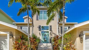 A two-story house with a front entrance, a staircase, and a garage. - Perfect Vacation Home! Pool, Lounge, and Ping Pong (Holmes Beach)