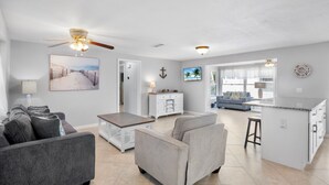 A spacious living area with a gray sofa set, a coffee table, and a kitchen island with a countertop. - Island Mojo! Family-Friendly Beach Escape! (Holmes Beach)