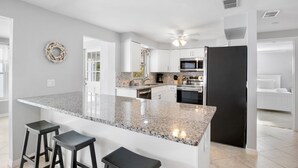 A modern kitchen with granite countertops, stainless steel appliances, and a black refrigerator. - Island Mojo! Family-Friendly Beach Escape! (Holmes Beach)