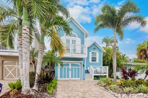 A two-story house with a blue exterior, a front porch, and a garage. - Enjoy Endless Fun with a Private Heated Pool at Key Largo Cottage! (Holmes Beach)