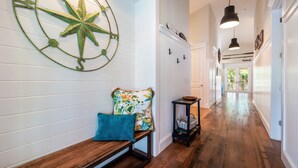 A hallway with a wooden bench, a compass wall decoration, and a black pendant light. - Cozy Pine Ave Cottage Near Beach (Anna Maria)