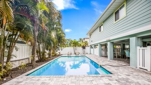 A swimming pool with lounge chairs and a covered patio area. - Beautiful Condo with Pool, Just Steps to the Beach! (Holmes Beach)