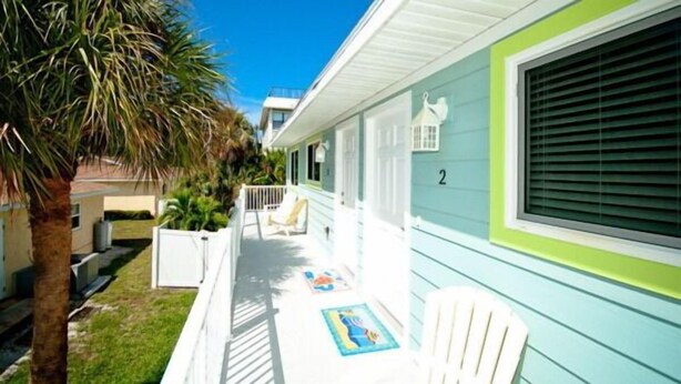 A two-story house with a porch, a palm tree, and a number '2' on the side. - Beautiful Condo with Pool, Just Steps to the Beach! (Holmes Beach)