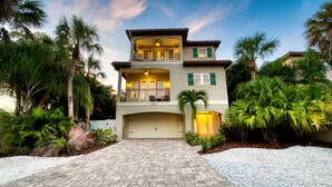 A two-story house with a covered driveway, a balcony, and a garage. - It's a Jungle Out There - Tropical Pool, Sunset Views, Game Room! (Holmes Beach)