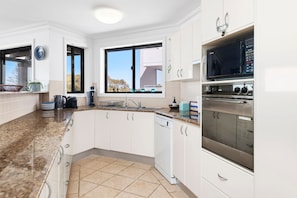 Eine moderne Küche mit weißen Schränken, einem Edelstahlbackofen und einem Fenster mit Blick.