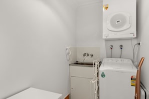 Ein Waschraum mit einer Frontlader-Waschmaschine und einem Trockner, einem Warmwasserbereiter und einer Schlauchaufrolle.