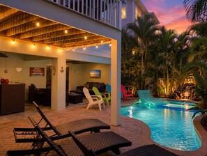 An outdoor pool area with lounge chairs and a covered seating area. - Holmes Beach Gem! Pool, Grill and Game Room! (Holmes Beach)