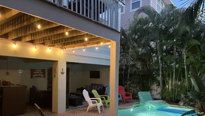 Une terrasse extérieure agrémentée de guirlandes lumineuses, une piscine et des chaises longues.