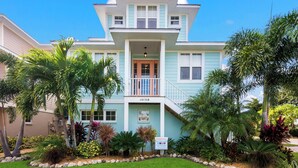 Une maison à deux étages dotée d’un balcon, d’un panneau indiquant la présence d’une piscine chauffée et d’un jardin bien entretenu où poussent différentes espèces de plantes.