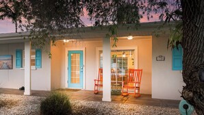 A house with a porch, a blue door, and two rocking chairs.
