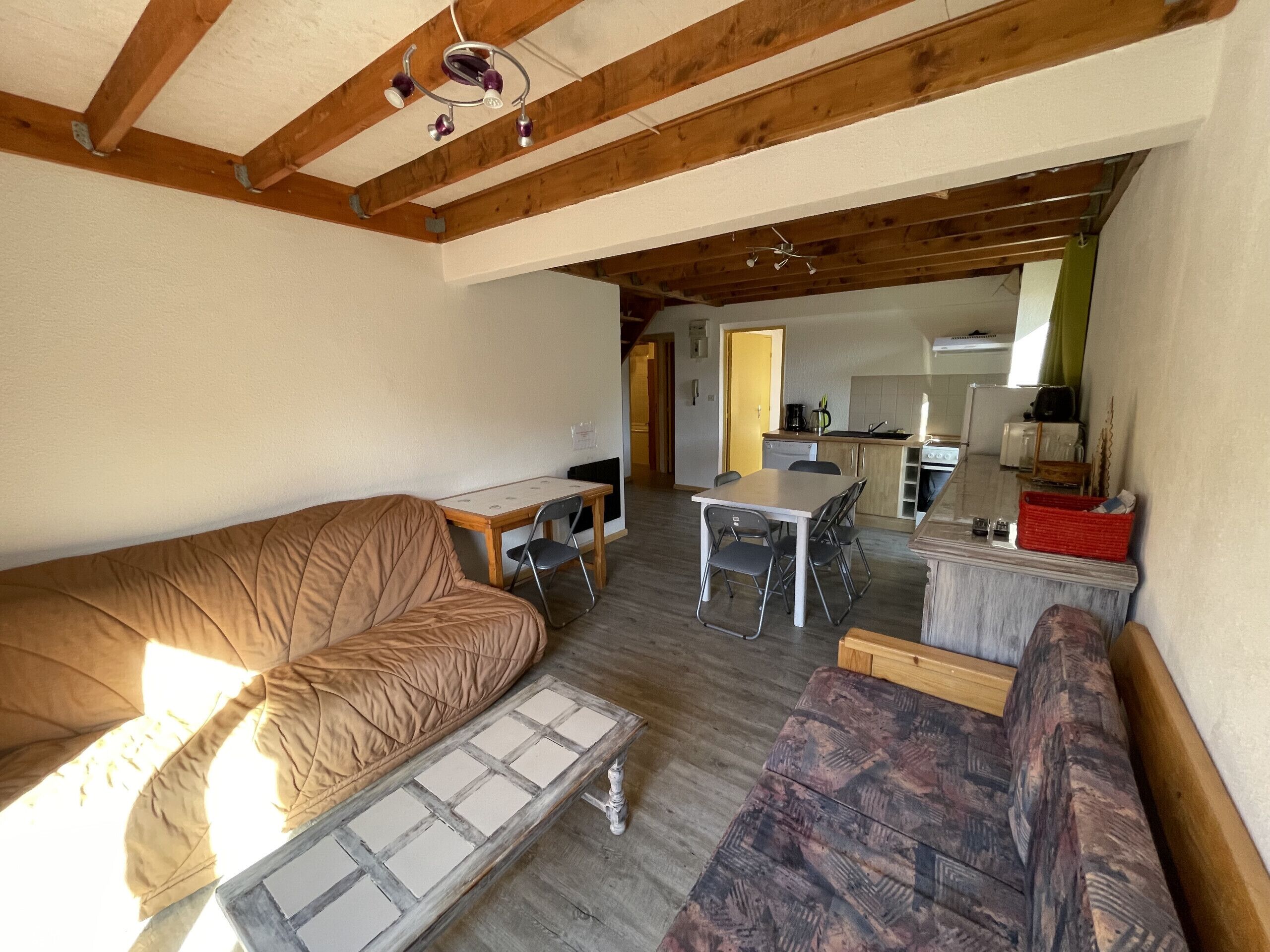 A compact living space with a sofa, a small table, and a kitchenette area.
