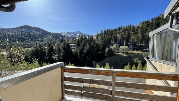 Un balcon offrant une vue sur une vallée boisée et des montagnes.