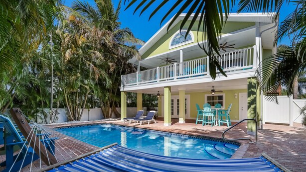 Un espace piscine aménagé avec un hamac, des chaises longues et un balcon donnant sur la piscine.