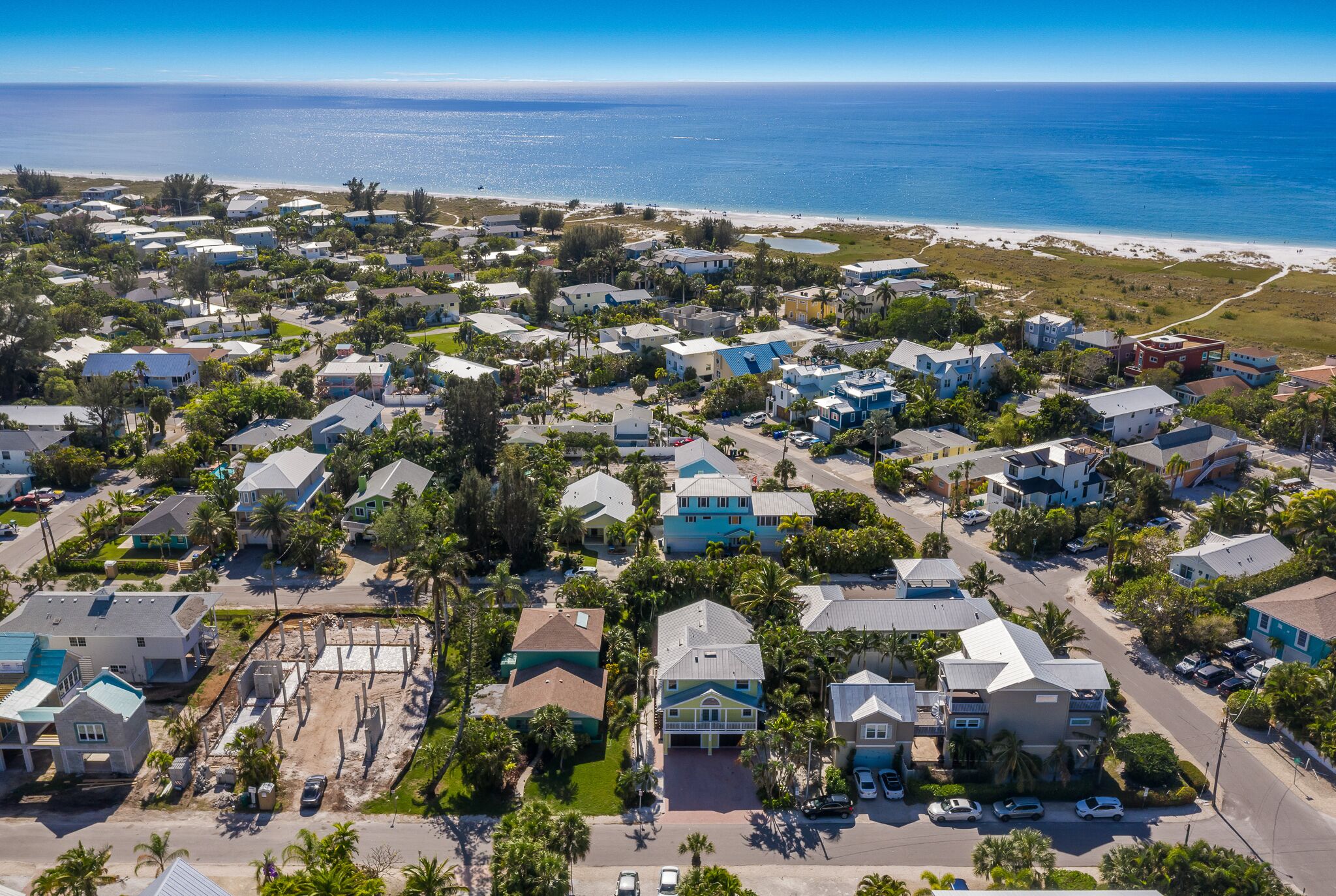 Vista aerea di una zona residenziale costiera con case, strade e spiaggia.