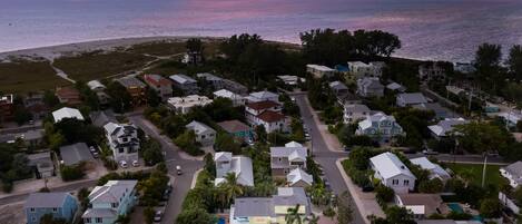 An aerial view of a residential area with houses, streets, and a beach in the background.