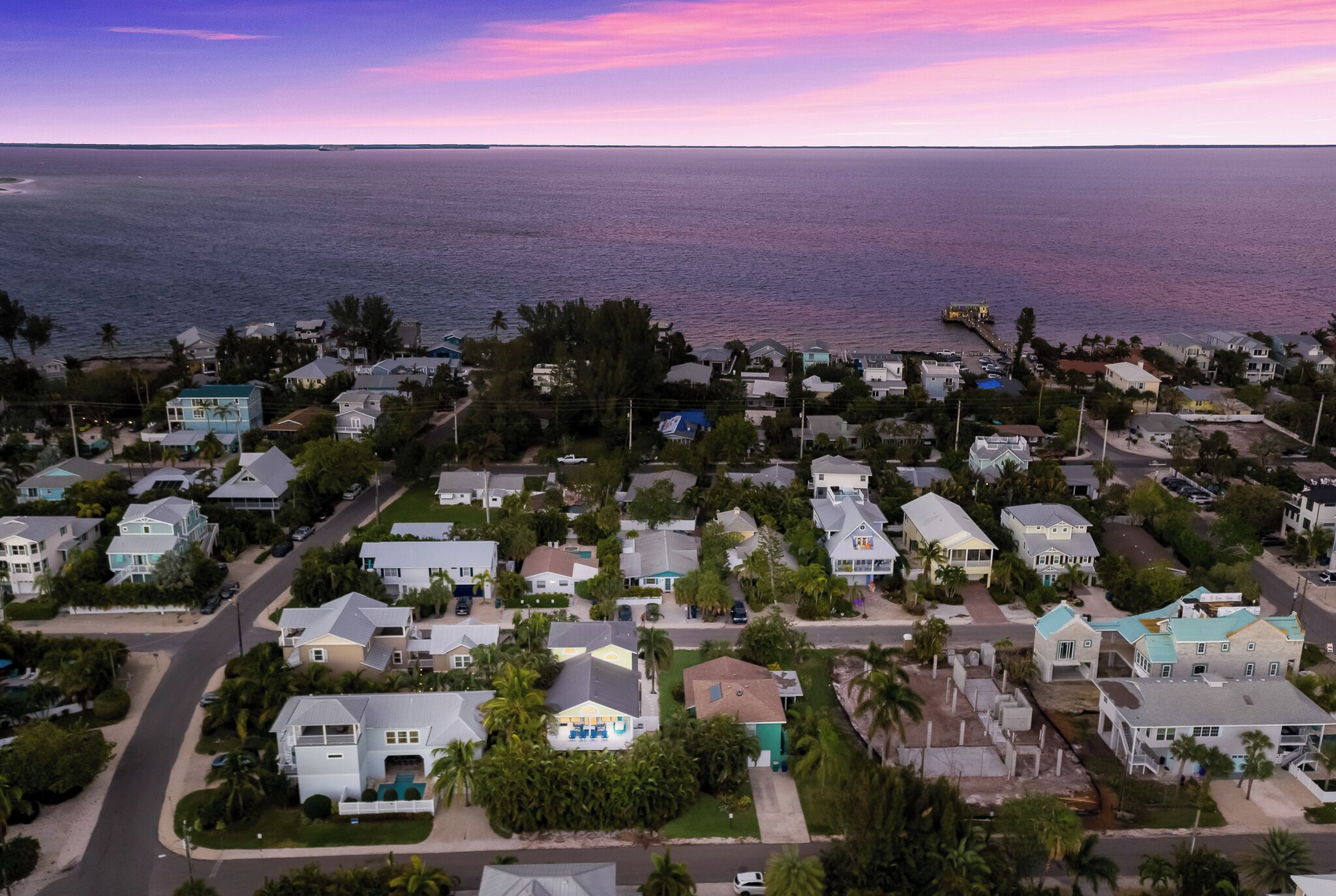 Vista aérea de uma área residencial costeira com casas, estradas e uma praia.