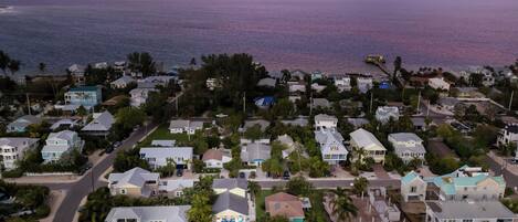 Vista aérea de uma área residencial costeira com casas, estradas e uma praia.