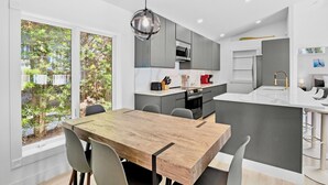 Uma cozinha moderna com armários cinza, uma mesa de jantar de madeira e uma luminária pendente.
