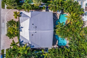 Vista aérea de um resort com piscina, palmeiras e uma área de estar coberta.