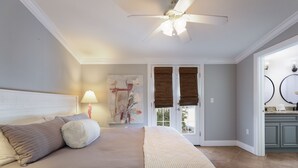 A bedroom with a bed, a nightstand, a lamp, a ceiling fan, and a view of the outside. - Beautiful Villa near the Beach with Pool! - Mermaid's Hideaway (Holmes Beach)