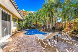 A backyard with a swimming pool, lounge chairs, and tropical plants. - Quiet North End Home Only 2 Blocks to Beach with Private Pool (Anna Maria)