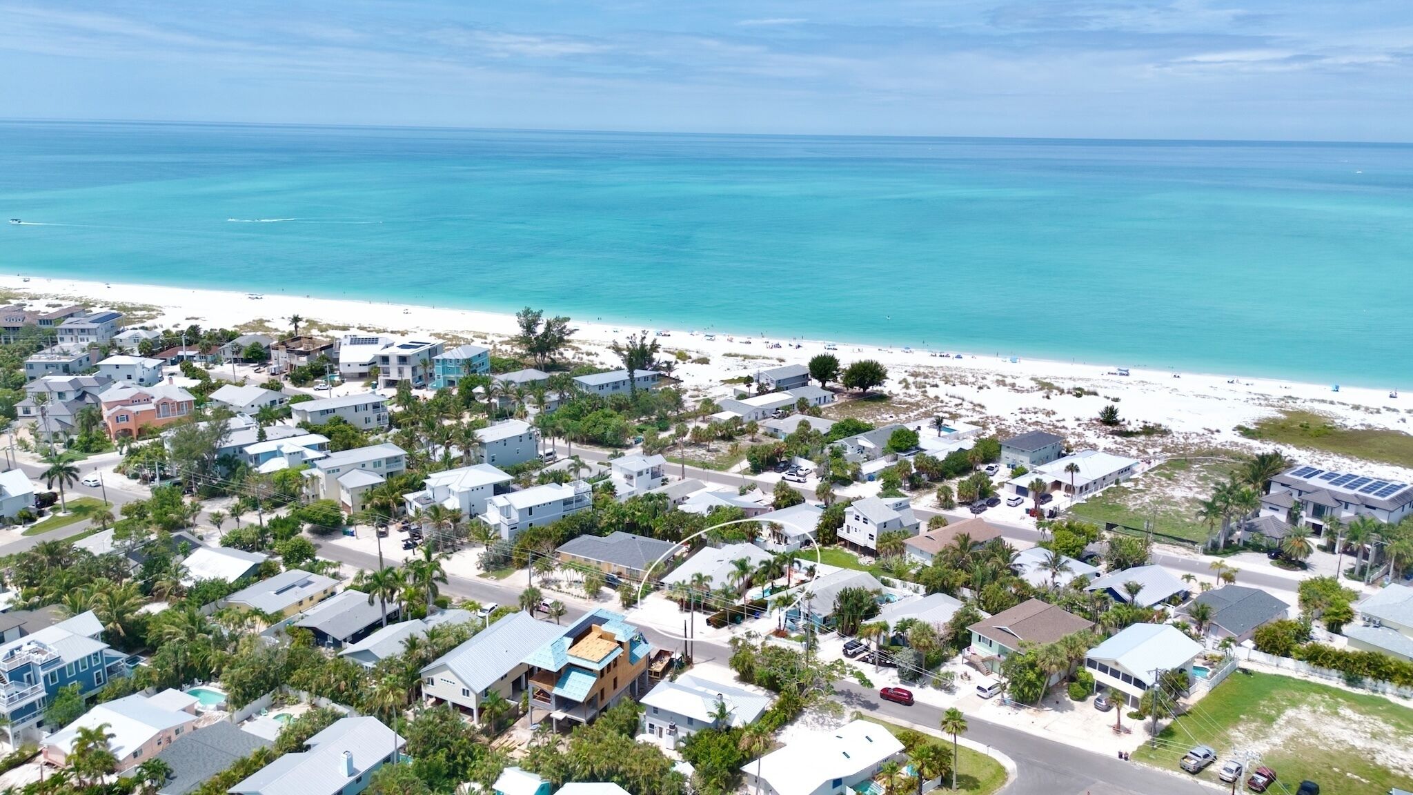 A coastal residential area with houses, a beach, and a clear view of the ocean.