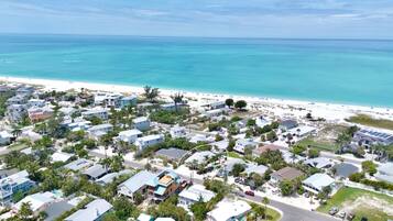 A coastal residential area with houses, a beach, and a clear view of the ocean.