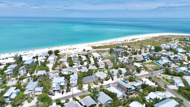 An aerial view of a coastal residential area with houses, a beach, and a clear view of the ocean. - Duplex with Heated Pool! 2 Blocks to Beach! - Turtle Crawl (Anna Maria)