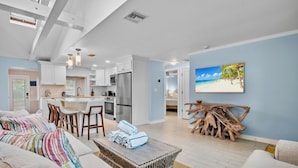 A modern kitchen with white cabinets, stainless steel appliances, and a dining area with a white table and chairs. - Duplex with Heated Pool! 2 Blocks to Beach! - Turtle Crawl (Anna Maria)
