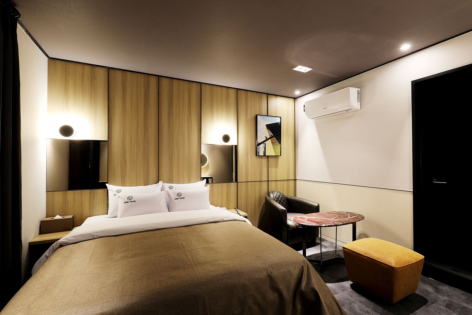 A hotel room with a bed, a desk, a chair, a small table, and a sofa.