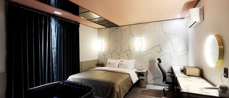 Una habitación de hotel moderna con cama, escritorio, silla y un ventanal con cortinas.